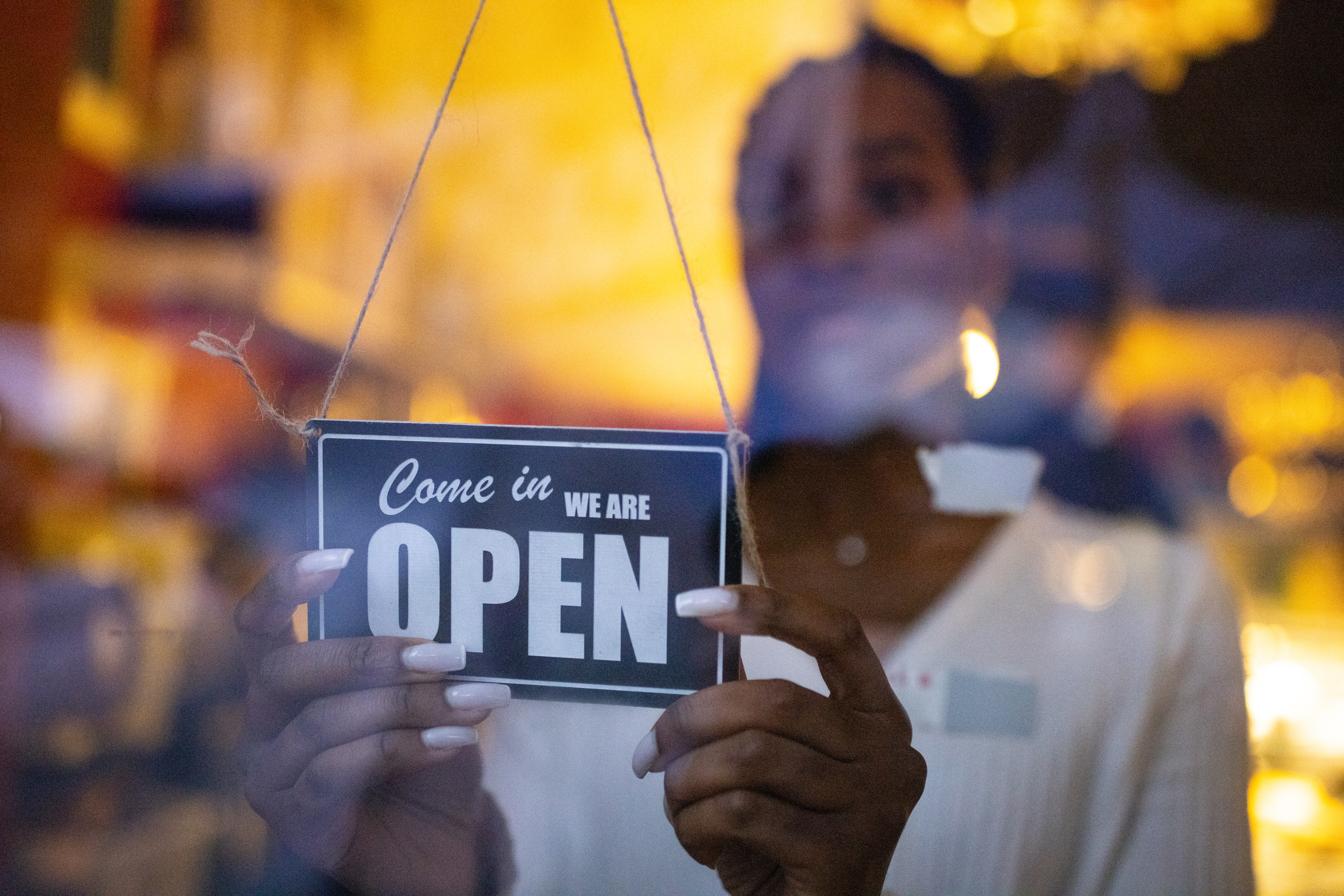 Business owner hanging an open sign at a cafe