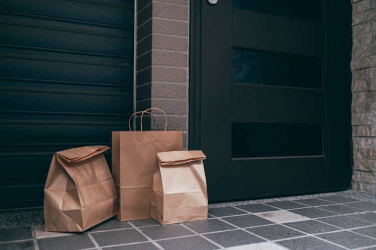 Takeaway meal packed in brown paper bag delivered to the front door of a residential building.