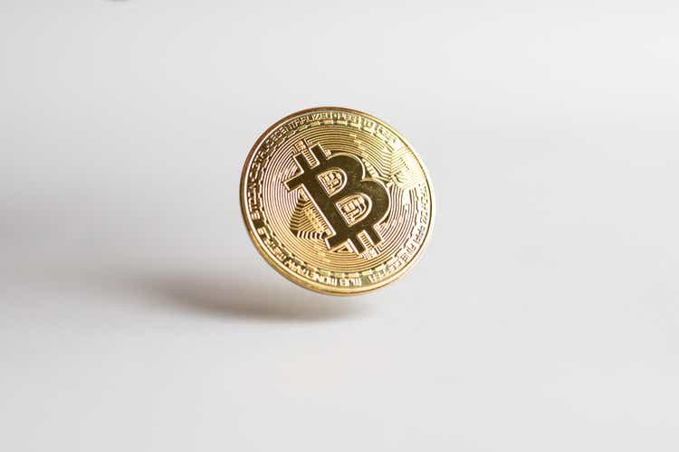 A gold Bitcoin floating above a white background
