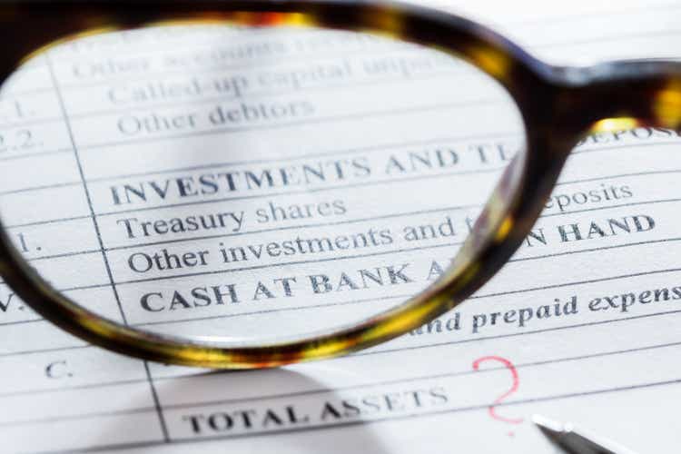 Balance sheet item “Investments and term deposits” through person eyeglasses and pen close it on a table