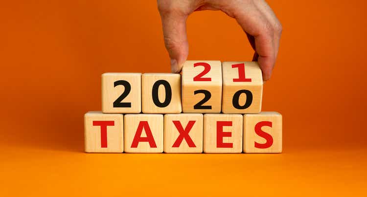 Business concept of planning 2021. Male hand flips wooden cubes and changes the inscription "Taxes 2020" to "Taxes 2021". Beautiful orange background, copy space.