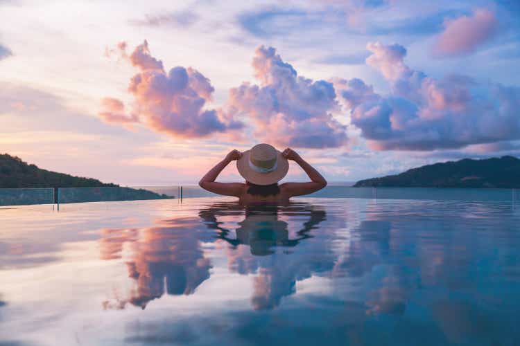 Asian travel bikini woman relax in infinity pool on phuket beach Thailand