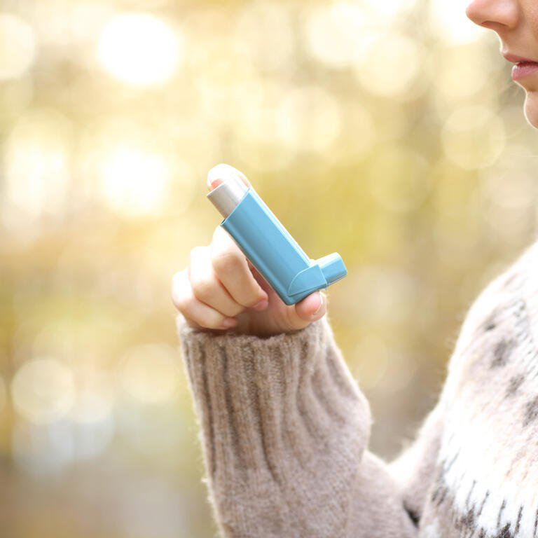 Woman hand holding asthma inhaler ready to use in winter