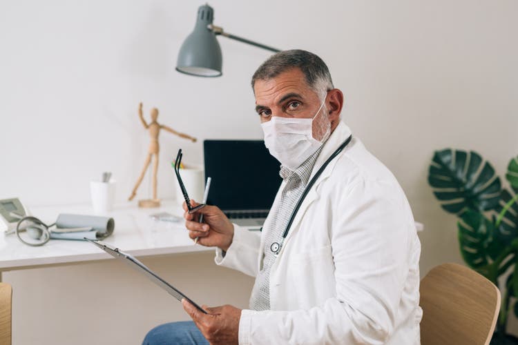 medico con maschera protettiva per il viso in posa