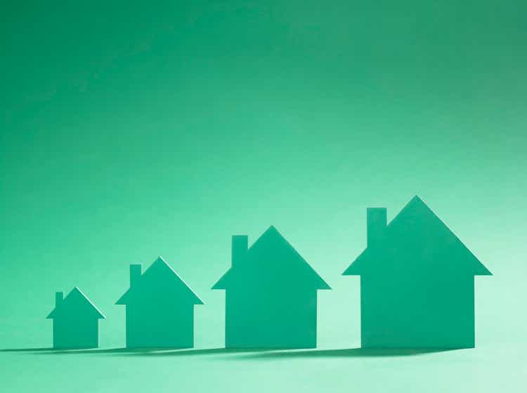 Four green cardboard cutout houses on green background of increasing size.