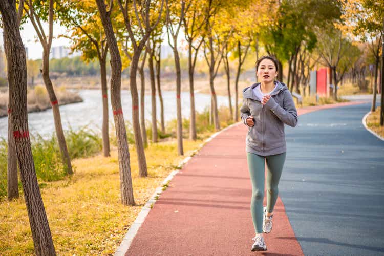 Young Asian female running in the city public park