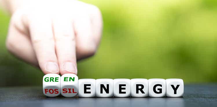 Hand turns dice and changes the expression "fossil energy" to "green energy".