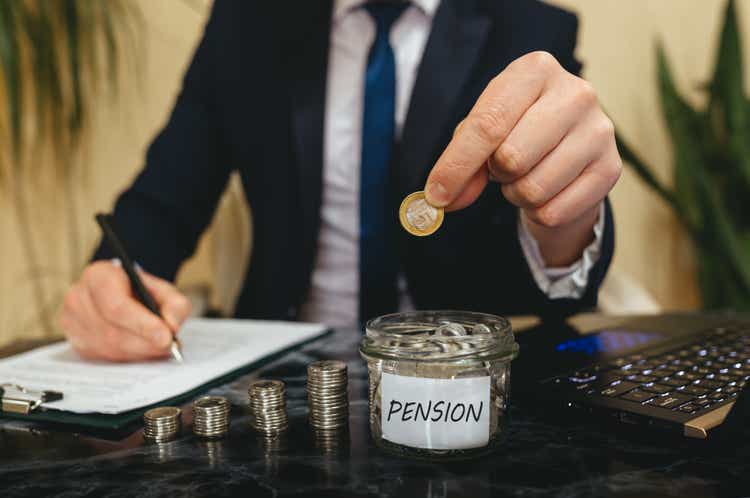 Hand putting coins in glass jar with pension label. Pension Fund. Financial condition of older people concept.