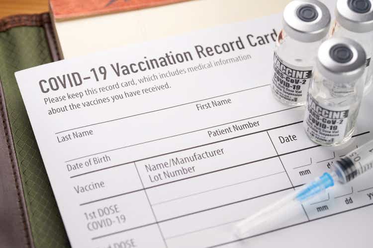 Covid-19 vaccination record card with vials and syringe.