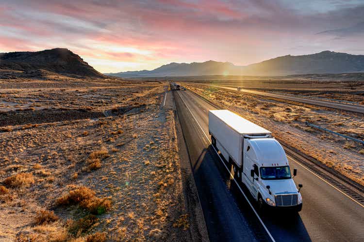 White Semi-Trailer Truck Heading down a four-lane Highway at Dusk