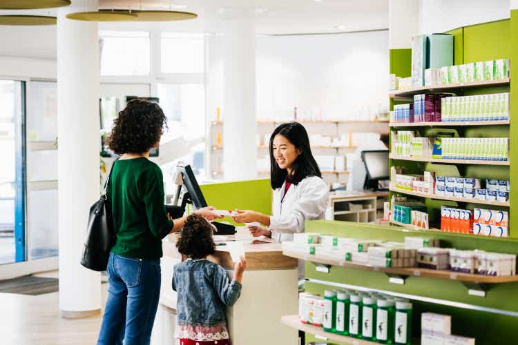 Small Family Being Served By Chemist At Local Pharmacy