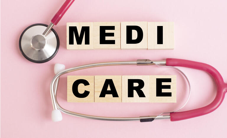 medicare word written on wood block and stethoscope on a pink background