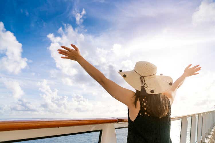 attractive carefree asian female woman casual cloth smile relax pleasure vacation time on cruise ship balcony with blue sky cloud background