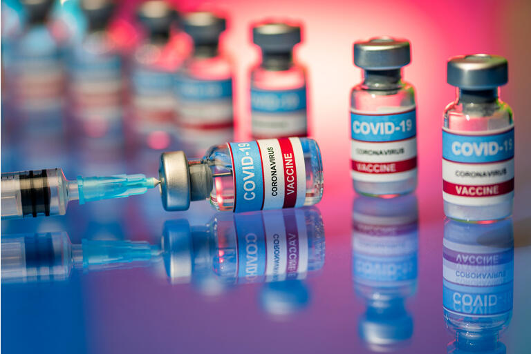 Vials and Syringe - Close up of Covid-19 vaccine on a reflective surface