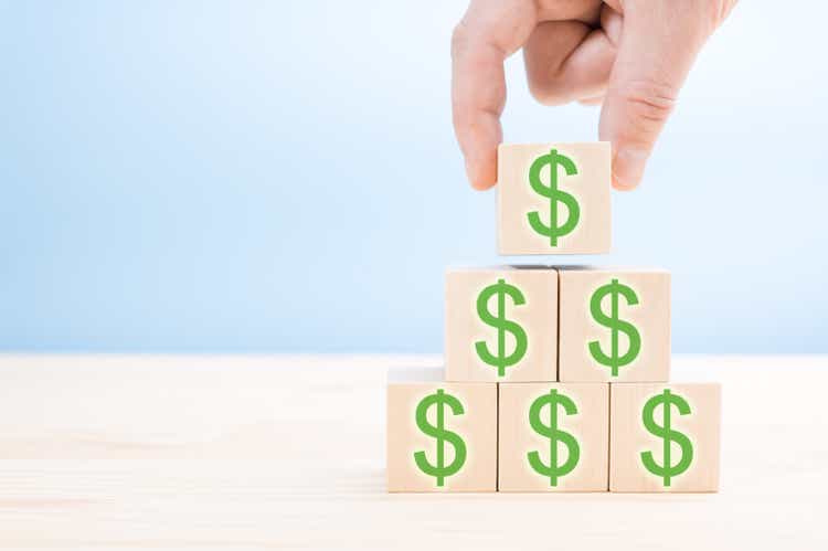 Hand of men arranging Wood block cubic stacking step up with green Dollar Sign Blue background. Business growth success process. Up Trend. Wooden block and dollar mark