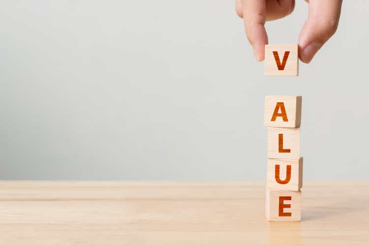 Hand of male putting wood cube block with word VALUE on wooden table