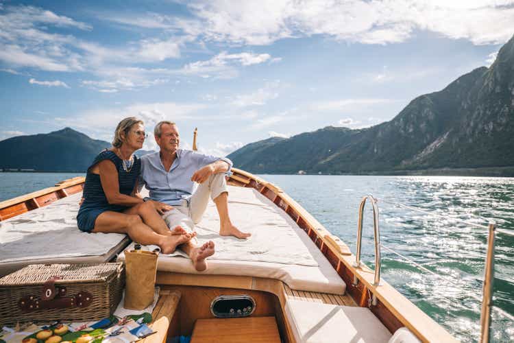 Mature couple relax on sailboat moving through Lake Lugano