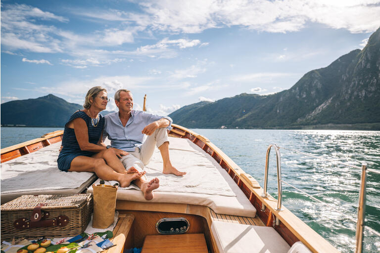 Mature couple relax on sailboat moving through Lake Lugano