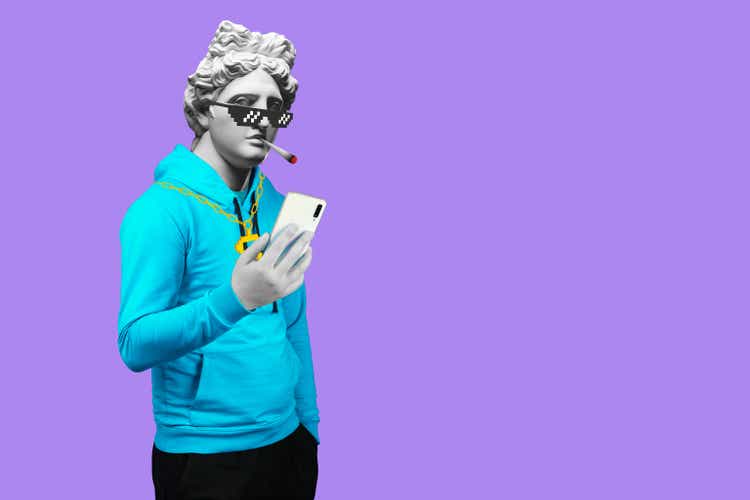 Modern art collage. Concept portrait of a man holding mobile smartphone using app texting sms message. Gypsum head of of Apollo. Man in suit. On a blue background.
