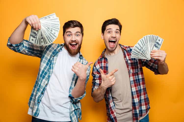 Portrait of a two excited oung men showing money