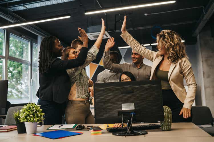 Happy multinational coworkers giving high five celebrating great teamwork result