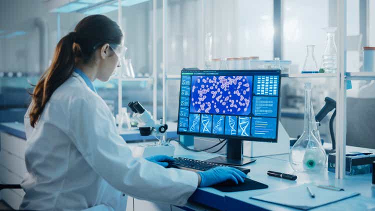 Medical Science Laboratory with Diverse Multi-Ethnic Team of Biotechnology Scientists Developing Drugs, Microbiologist Working on Computer with Display Showing Gene Editing Interface.
