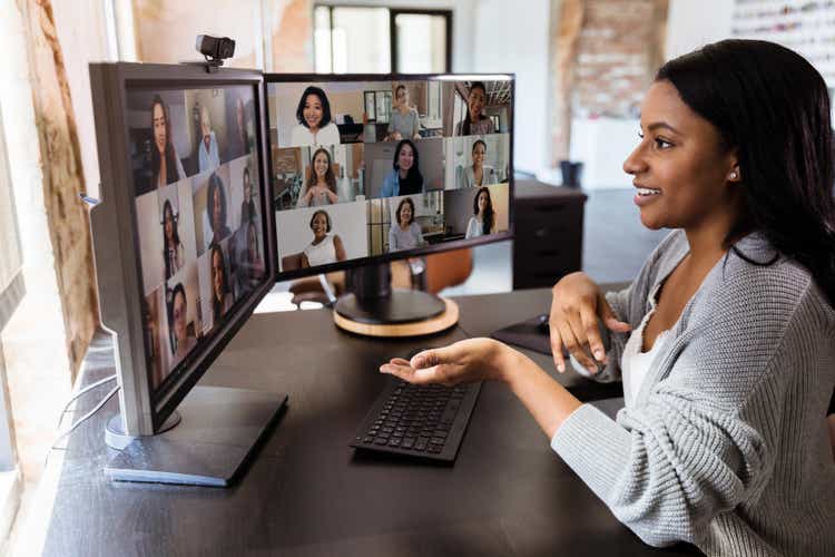 During COVID-19, attractive woman gestures during virtual meeting with colleagues