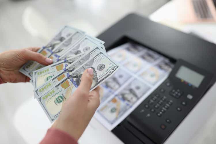 Woman printing dollar bills on printer closeup