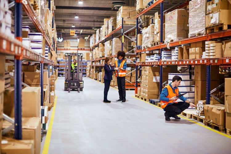 General view of a warehouse aisle with workers.
