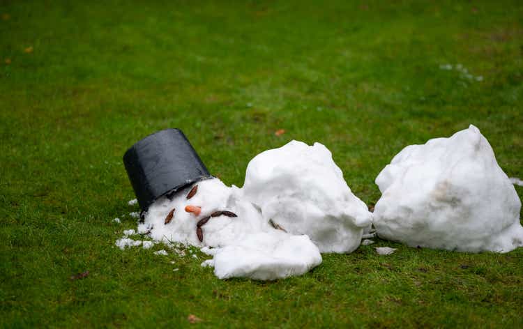 A melted snow man with a sad face as symbol of the end of the winter.