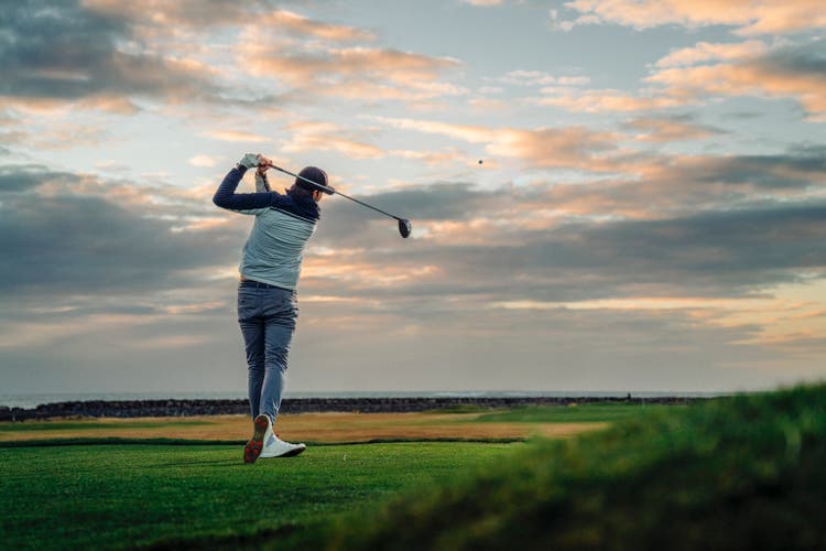 Male athlete teeing off at course during sunset