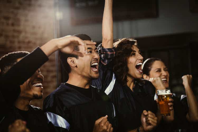 Excited female fan cheering while watching football game on TV