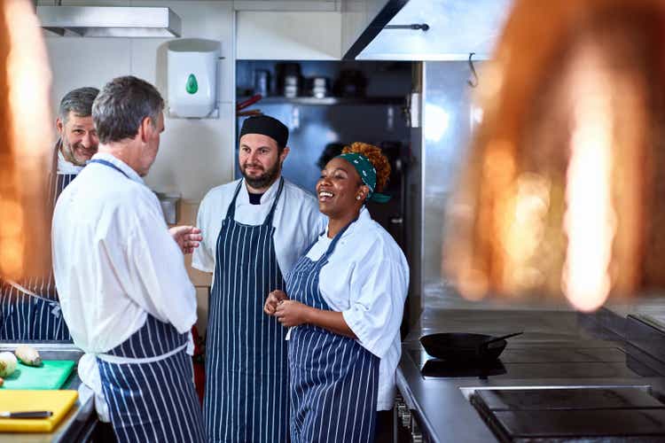 Four chefs chatting in commercial kitchen