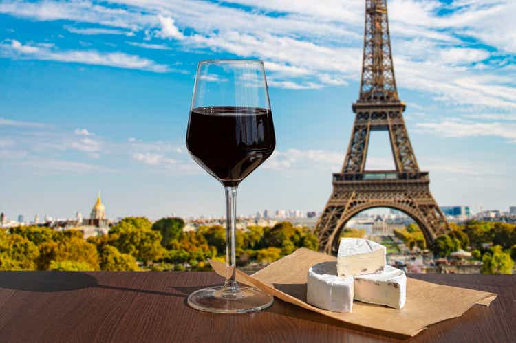 Бокал вина с сыром бри на Эйфелевой башне и фоне горизонта Парижа