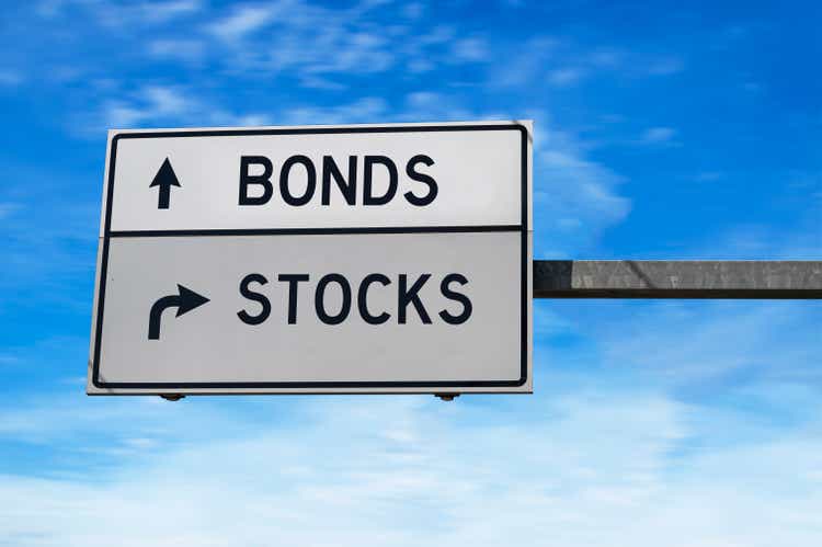 Road sign with words bonds and stocks. White two street signs with arrow on metal pole on blue sky background.