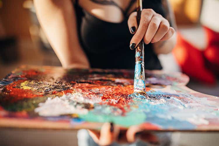 Female artist dipping paintbrush in colors for painting