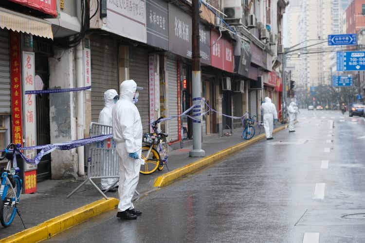 Medical staff in white hazmat suit on street