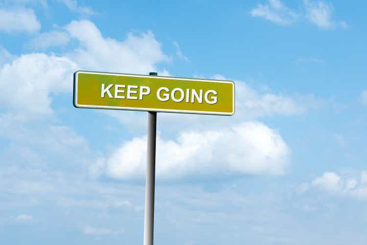 Keep Going. Road sign against a blue cloudy sky. Achievement of the goal. Achieving success.