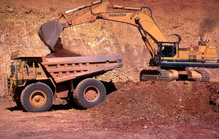 Large bucket scoop loads gold ore intoa giant dump truck