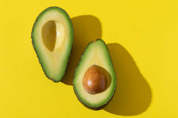 Avocado halves with trendy hard light and hard shadow on yellow background