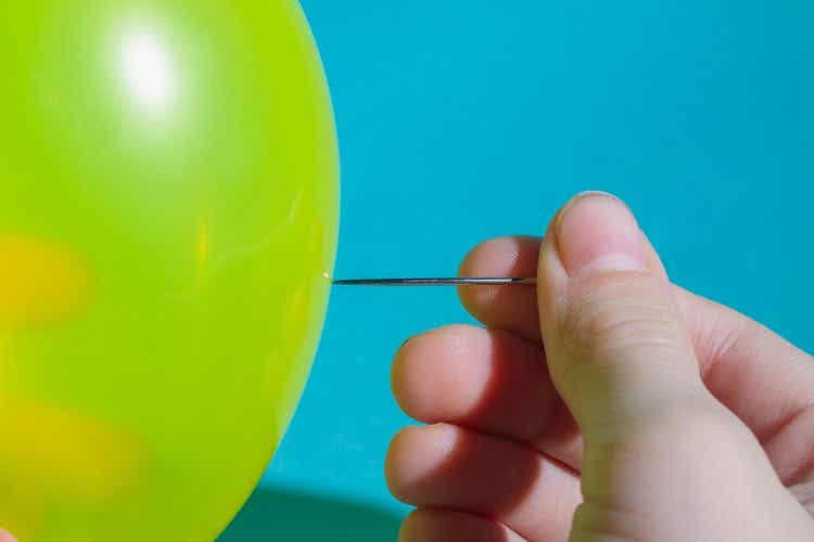 Pop the balloon with a sharp needle. Hold the sewing needle in your hand