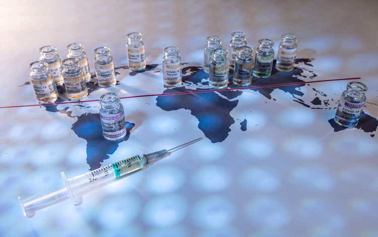 A conceptual image of a world globe map with vials for the global SARS/COVID pandemic vaccine war, with vaccine hoarding, restricting equal access to vaccines across the world, caused by vaccine nationalism and lack of vaccine solidarity