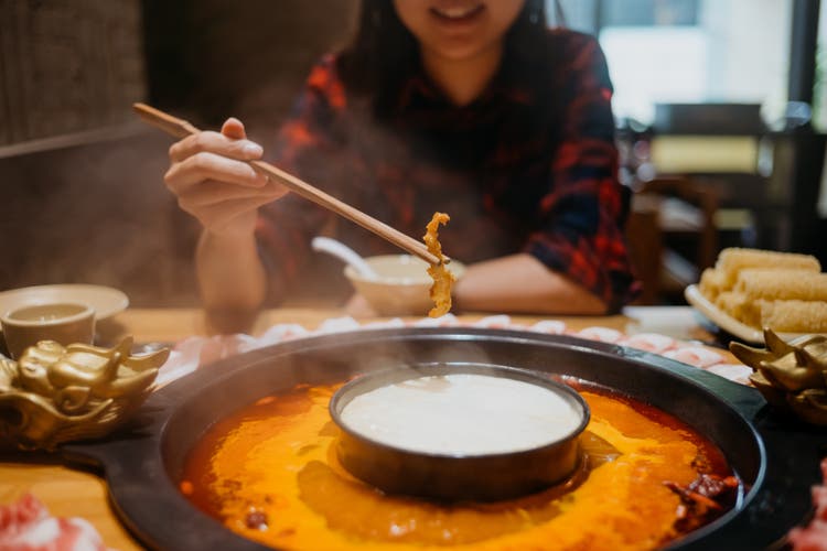 Young asian woman eating chinese hot pot