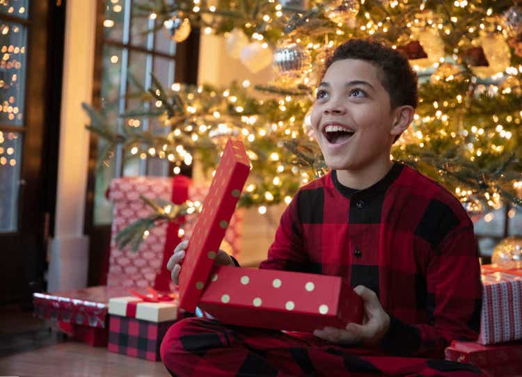 Chico adolescente de raza mixta abriendo regalos de Navidad