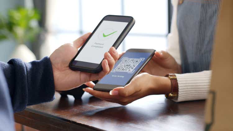 Customer using phone for payment at cafe restaurant, cashless QR code technology and money transfer concept