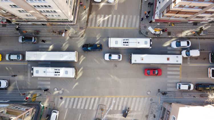 Aerial view of the city traffics at the center. Vehicles are moving on the road between buildings.