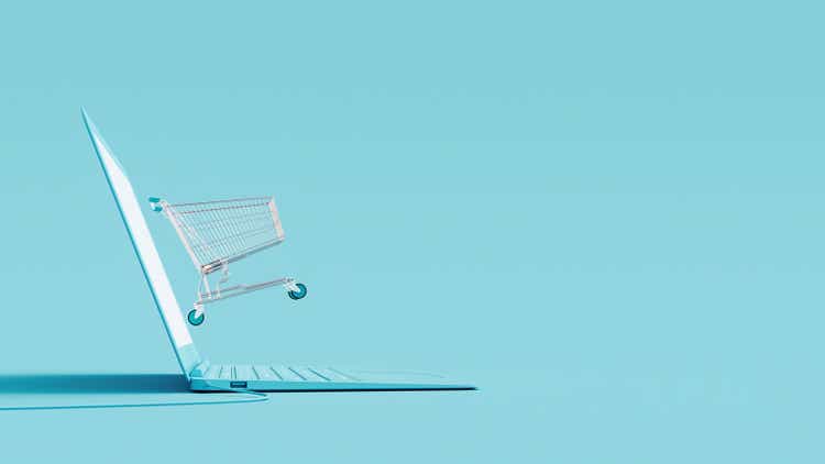 Online shopping concept. Laptop and shopping cart on blue background