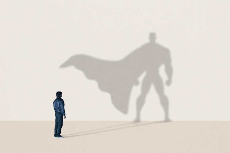 Young man standing in front of superhero shadow