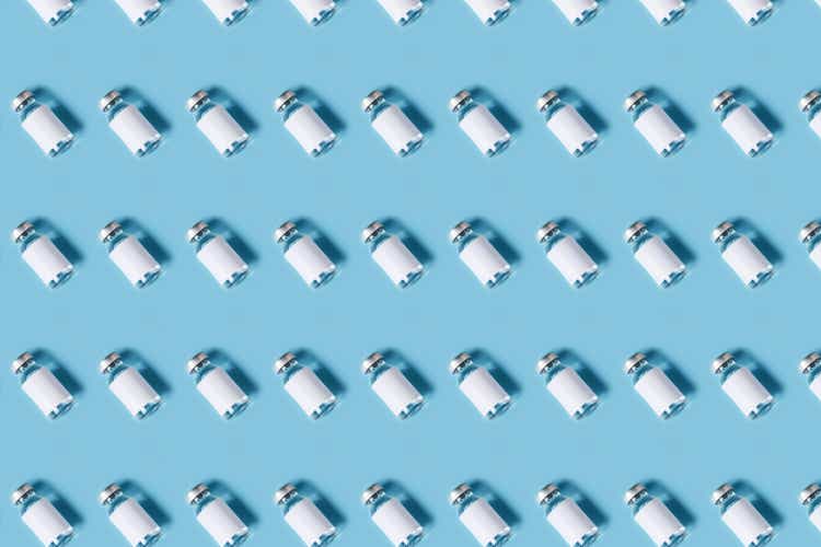 Vial with COVID-19 medicinal vaccine. Medical background as pattern. Flat lay style.