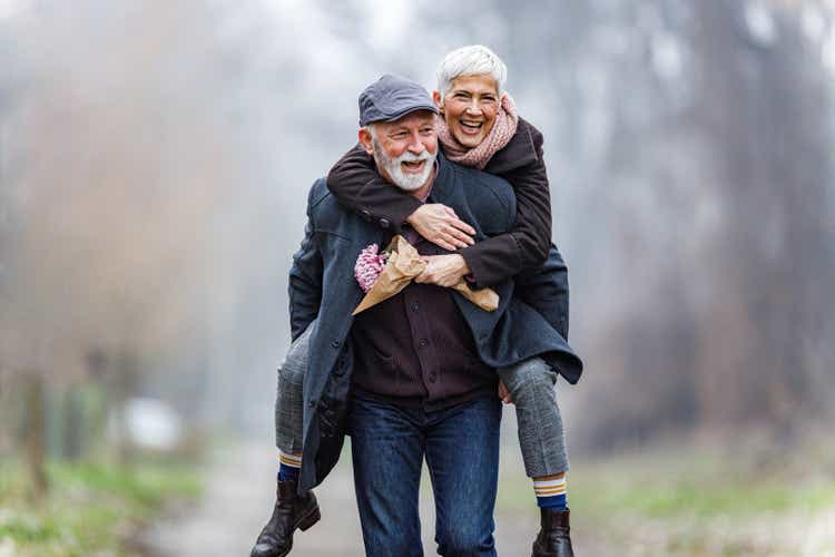 Playful mature couple piggybacking in winter day.